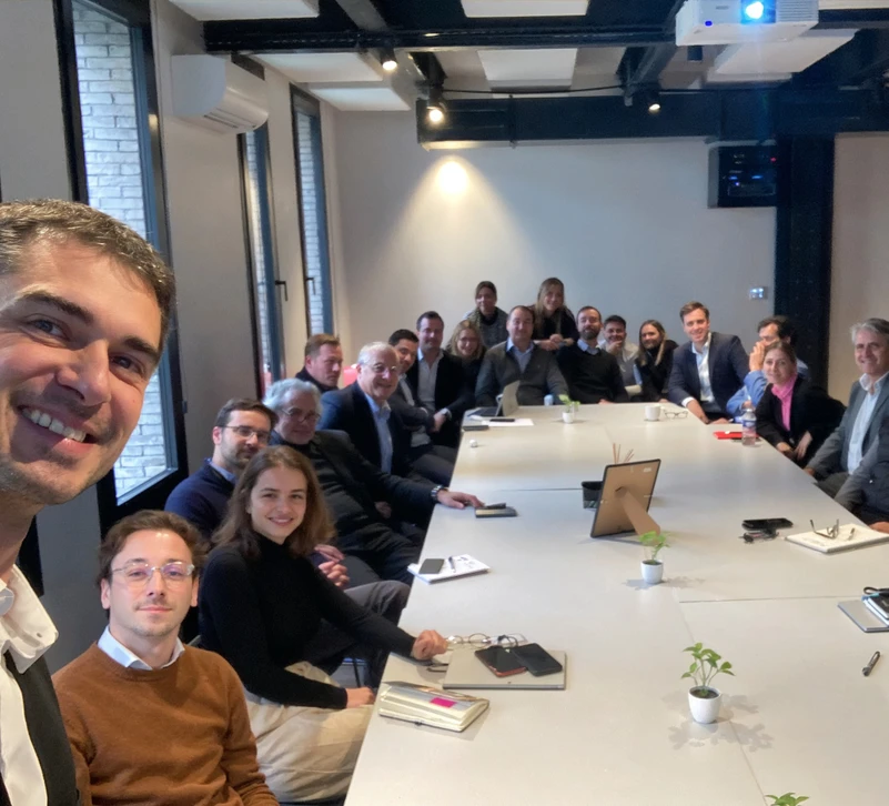 Espace de travail collaboratif avec quatre personnes utilisant ordinateurs portables et tablettes autour d'une table en bois